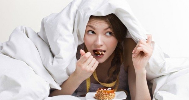 garota comendo abaixo das cobertas.
