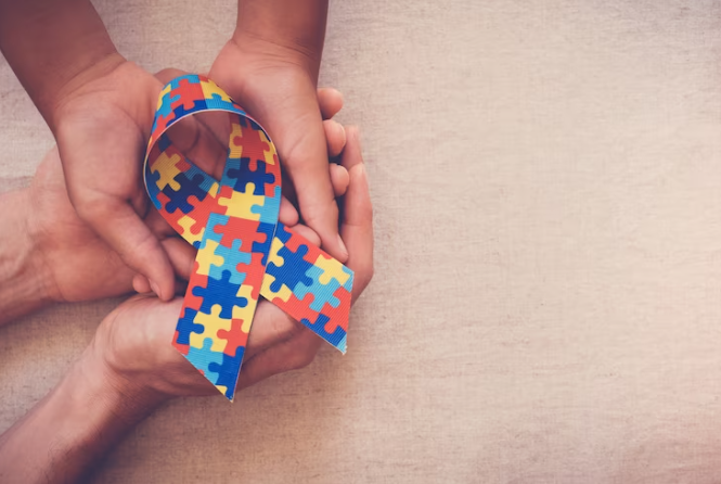 Mãos que seguram o símbolo do autismo.